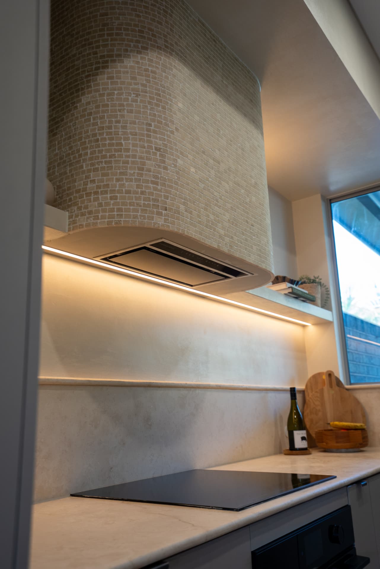 Limestone splashback & shadow-line shelf — Full-height limestone splashback with a floating shelf and concealed lighting.