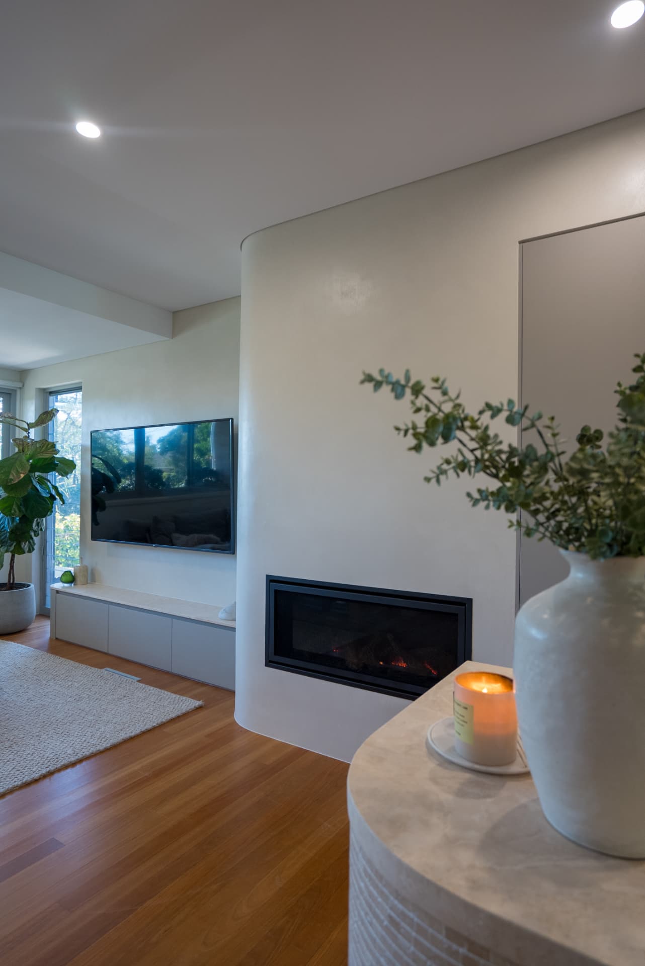 Living room renovation with curved rendered fireplace by Devise Constructions